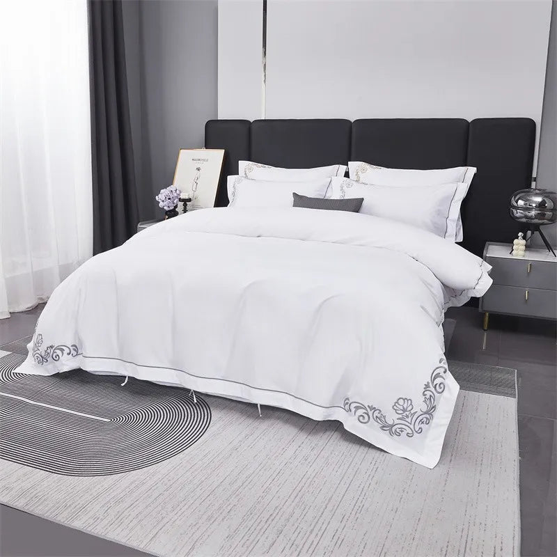 White bedding set with floral embroidery on a bed in a modern bedroom.