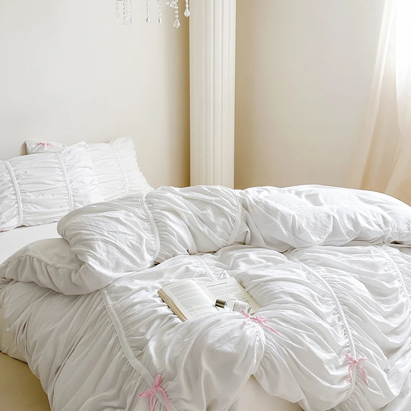White comforter with pink accents on a bed in a softly lit room.